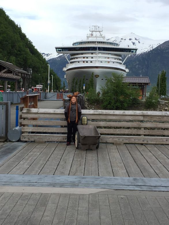 My son standing in front of the Norwegian Bliss docked in Skagway